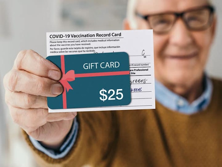 Man holding vaccination card and gift card together