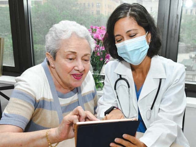 Provider assisting elderly patient with tablet device
