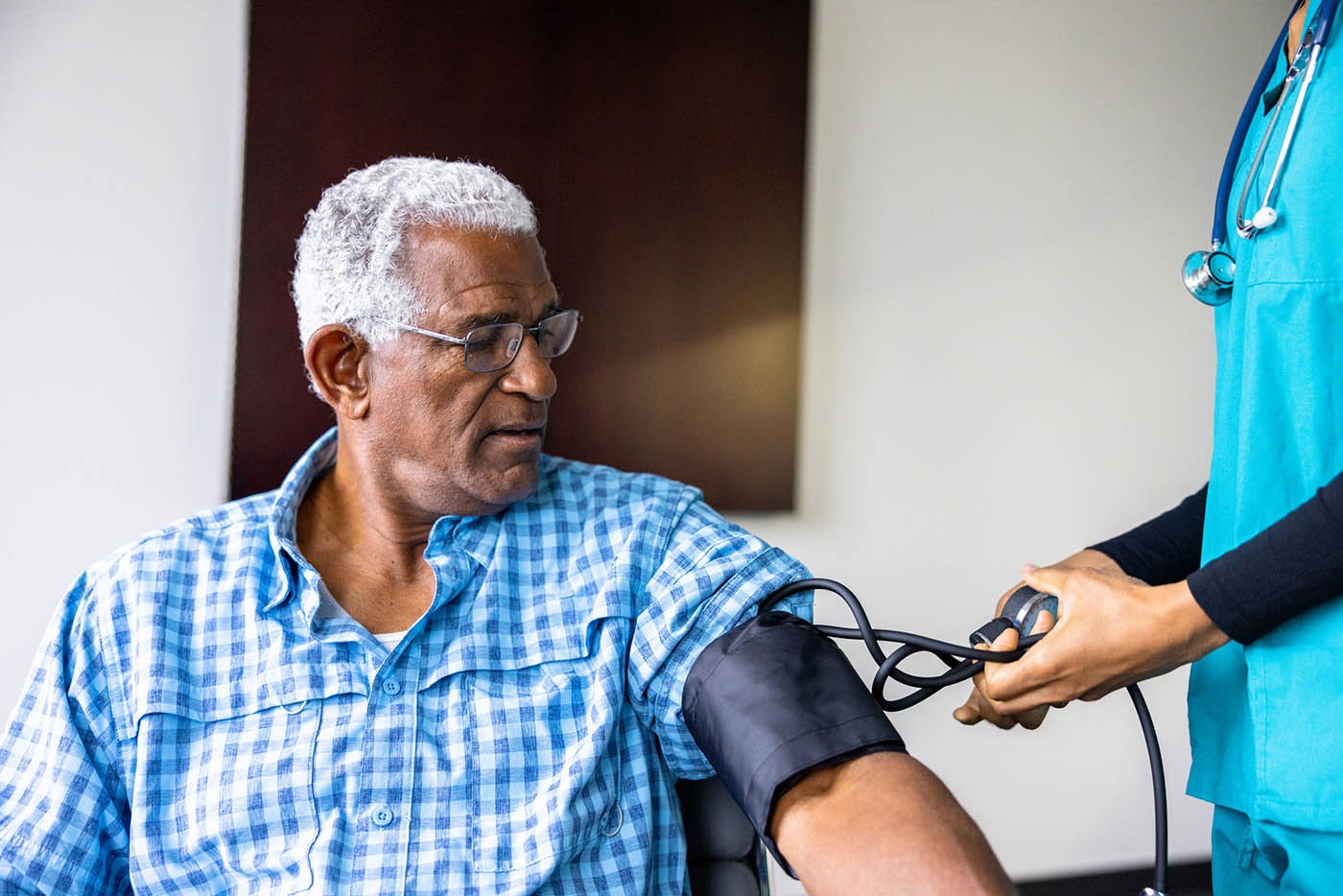Nurse meeting with a senior black male patient taking his blood pressure
