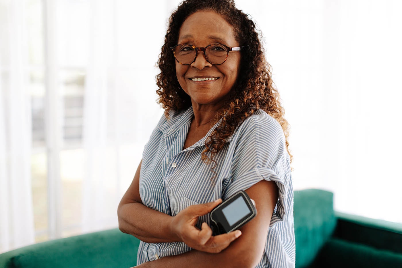 Portrait of a woman using continuous glucose monitoring to manage her diabetes at home.